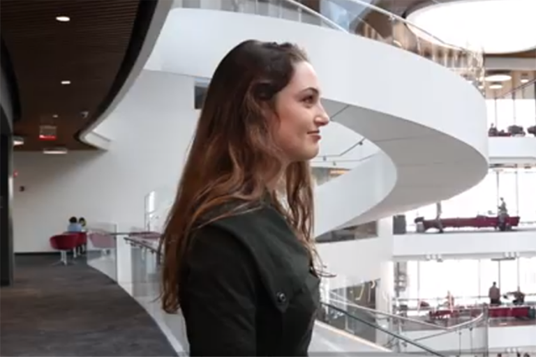 female student with white spiral staircase in background in ISEC building