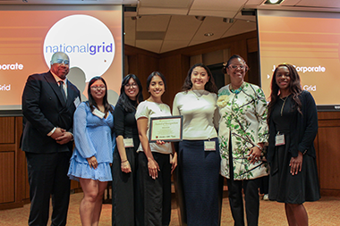 students stand with two national grid representatives